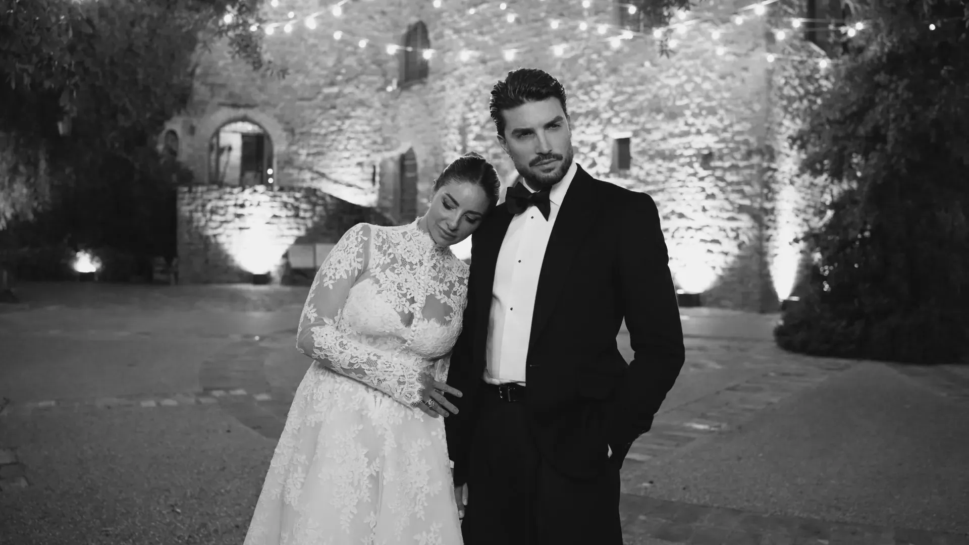 Sposi nel cortile illuminato di un castello, fotogramma in bianco e nero